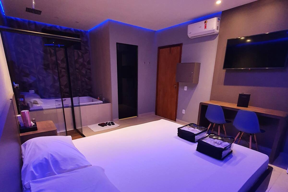 Ein modernes Schlafzimmer mit einem großen Bett, einem Schreibtisch und einem Fernseher.