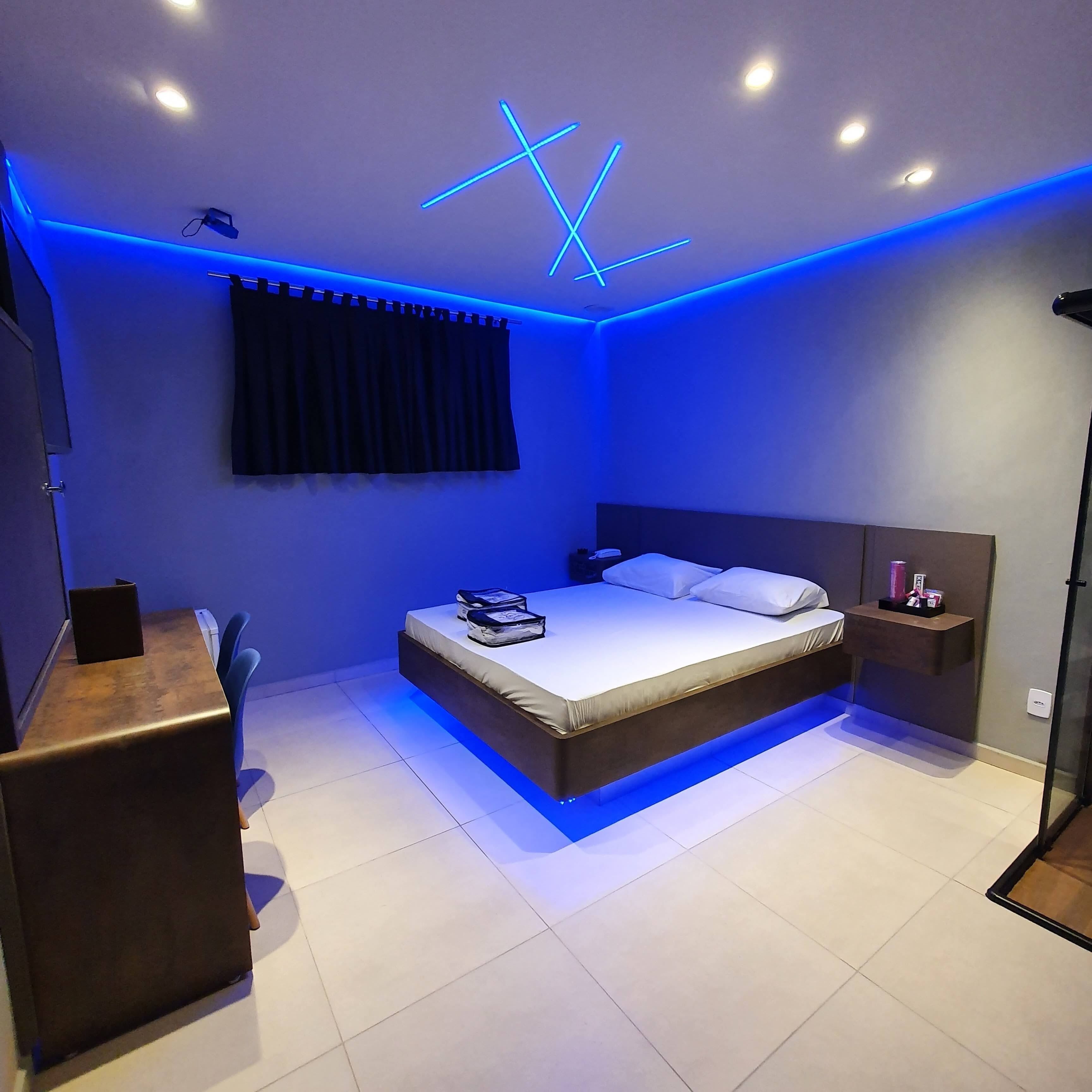 A modern bedroom with a bed, bedside tables, a desk, and a ceiling light fixture.