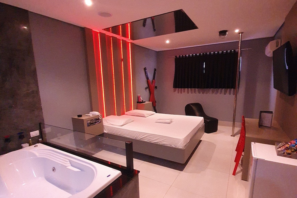 Ein modernes Schlafzimmer mit einem großen Bett, einem separaten Badezimmer mit Badewanne und einem an der Wand montierten Fernseher.