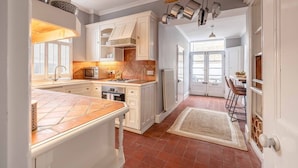A kitchen with white cabinets, a microwave, and hanging pots. - Stylish 3 Bdr Home Central Windsor By Tempstay (Berkshire)