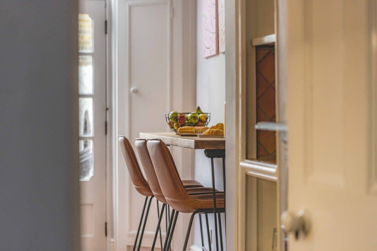 A dining area with a table, chairs, and a bowl of fruit.
