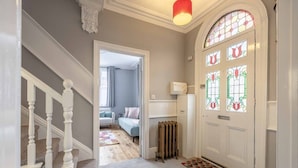 A hallway with a white door, radiator, and a patterned rug. - Stylish 3 Bdr Home Central Windsor By Tempstay (Berkshire)