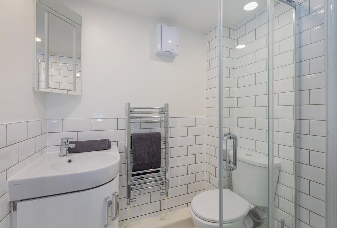 Une salle de bain moderne avec un lavabo blanc, un miroir et une douche en verre.