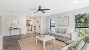 A modern living room with a sofa, a coffee table, and a ceiling fan.