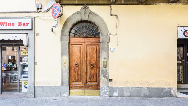 Un edificio con un puerta doble de madera, un letrero de bar de vinos y un letrero de cajero automático.