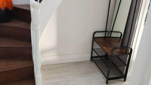 Una escalera con barandas blancas y un estante metálico negro adosado a la pared.