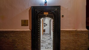 Une porte d’entrée sur laquelle est apposée une enseigne indiquant « Maison Solanes », et un sol orné de motifs.