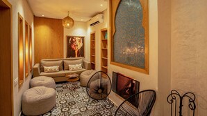 Un salon chaleureux avec un canapé, des poufs, un tapis à motifs et une œuvre d’art murale originale.