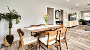 Un comedor con una mesa y sillas de madera, una planta en maceta y un jarrón con flores.