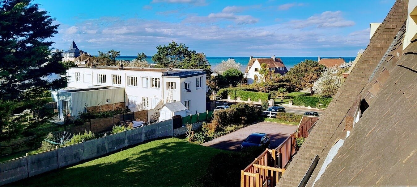 Un quartiere residenziale con una casa bianca, un garage e vista sul mare.