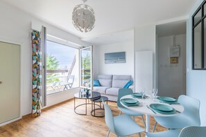 A modern dining area with a round table, teal chairs, and a view of the outdoors.