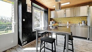 Une cuisine moderne dotée d’un grand îlot central, d’appareils électroménagers en acier inoxydable et offrant une vue sur l’extérieur.