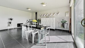 Une cuisine moderne avec un coin repas, comprenant un plan de travail noir, des chaises transparentes et un meuble blanc.