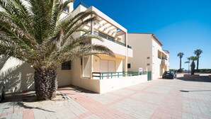 A modern building with a balcony, palm tree, and paved walkway.