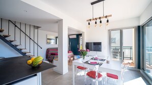 A modern kitchen with a dining area, a staircase, and a large window.