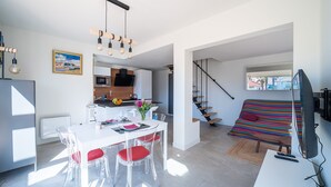 A modern living space with a dining area, kitchen, and a colorful striped sofa.