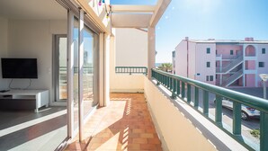 A balcony with a TV, sliding glass doors, and a view of a pink building.