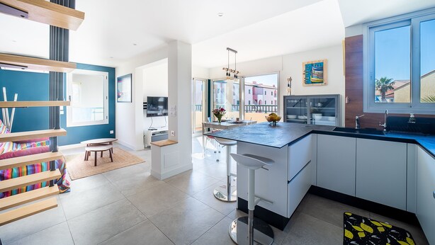 A modern kitchen with white cabinets, a black countertop, and a large window.