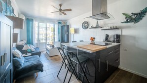 Una cocina moderna con una isla central, taburetes de bar y un área de comedor con un sofá.