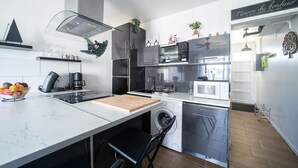 Una cocina moderna con lavadora integrada, microondas y cafetera.