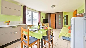 Une pièce comprenant une table à manger, des chaises, un lit, un téléviseur et un réfrigérateur.