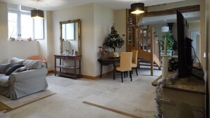 Ein Wohnzimmer mit einer Couch, einem Esstisch mit Stühlen, einem Weihnachtsbaum, einer Treppe und einem Fernseher.