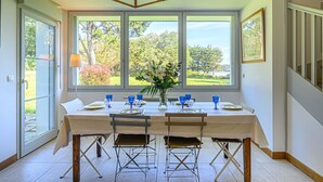 A dining area with a table set for four, large windows with a view of trees and a beach, and a sign indicating 'BEACH'.
