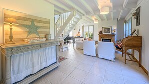 A spacious living room with a fireplace, a piano, and a staircase leading to another level.