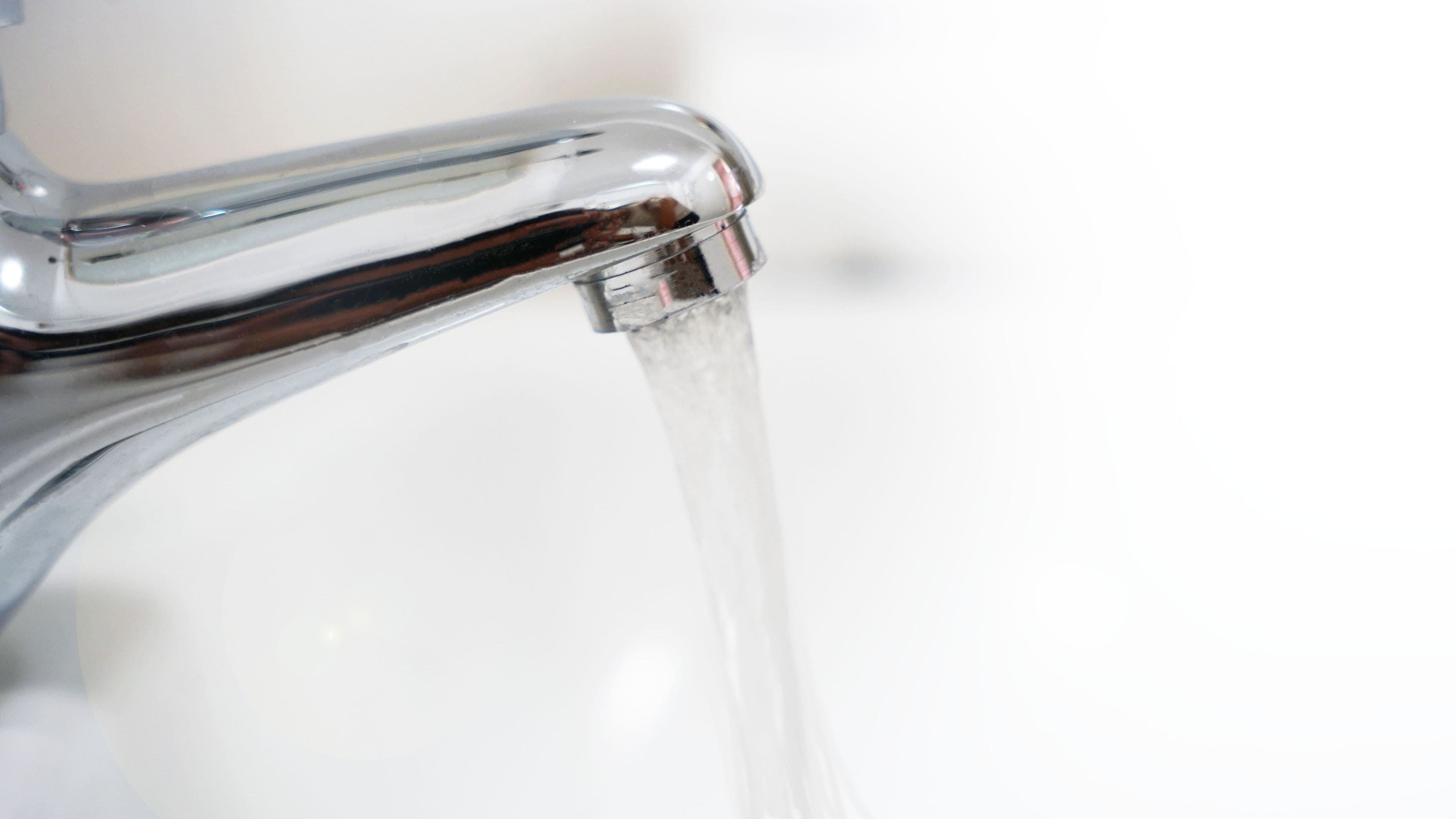 A close-up of a chrome faucet with water flowing from it.