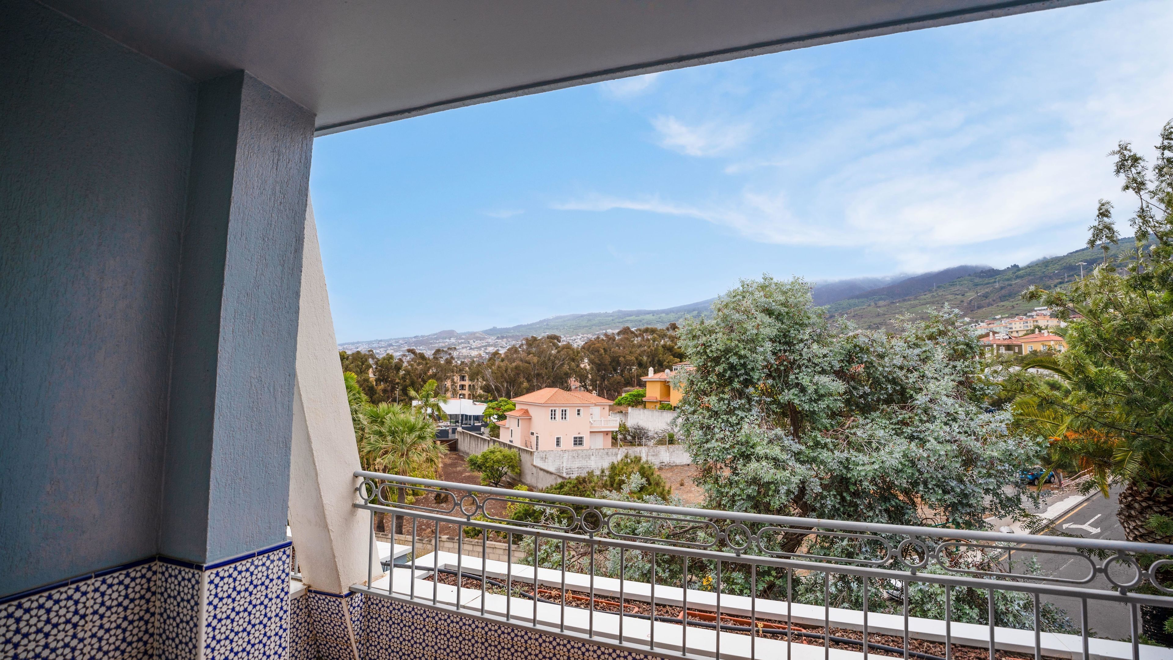 A balcony with a view of a residential area, including houses and trees.