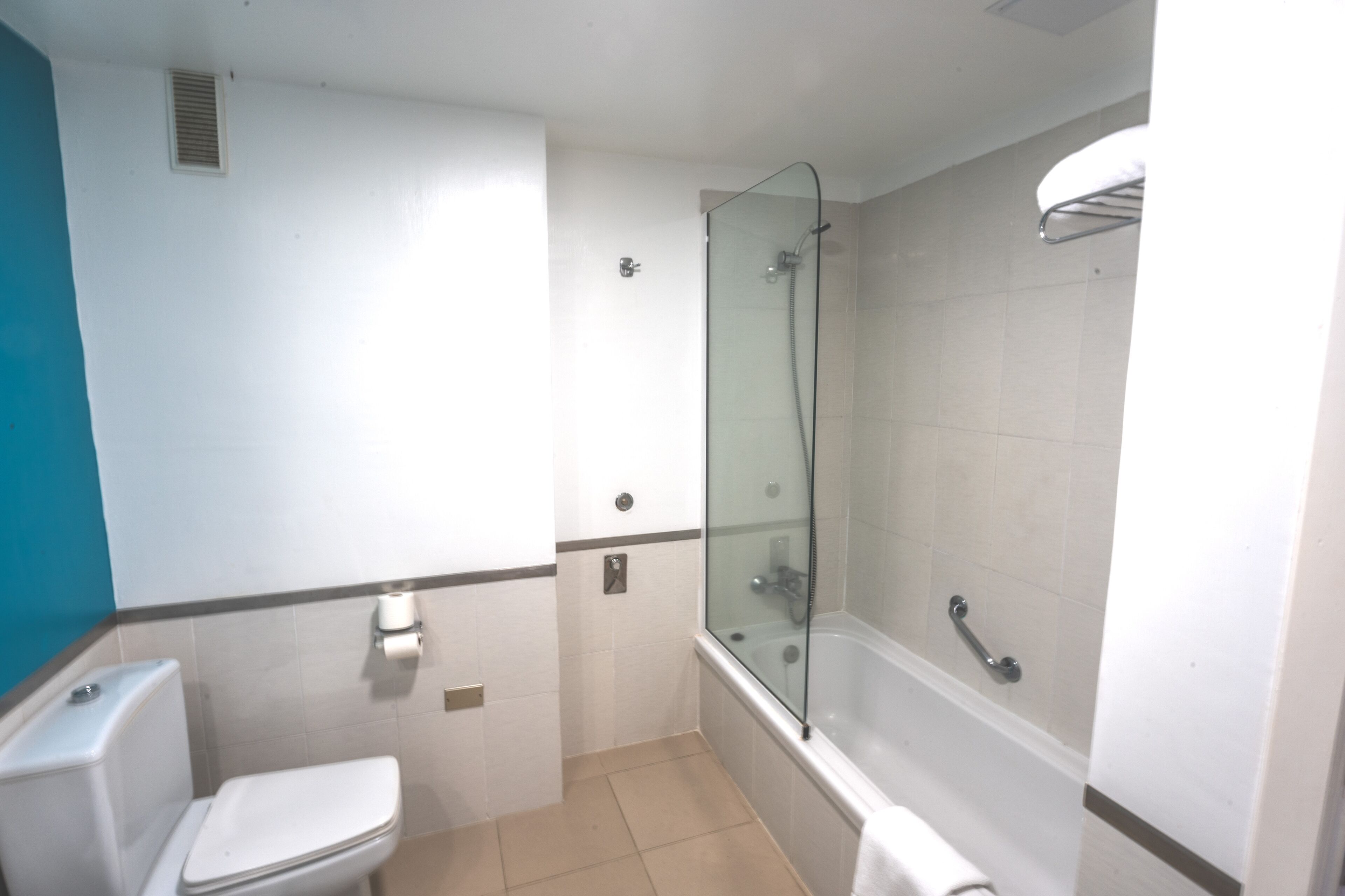 A bathroom with a toilet, a glass-enclosed shower, and a bathtub.