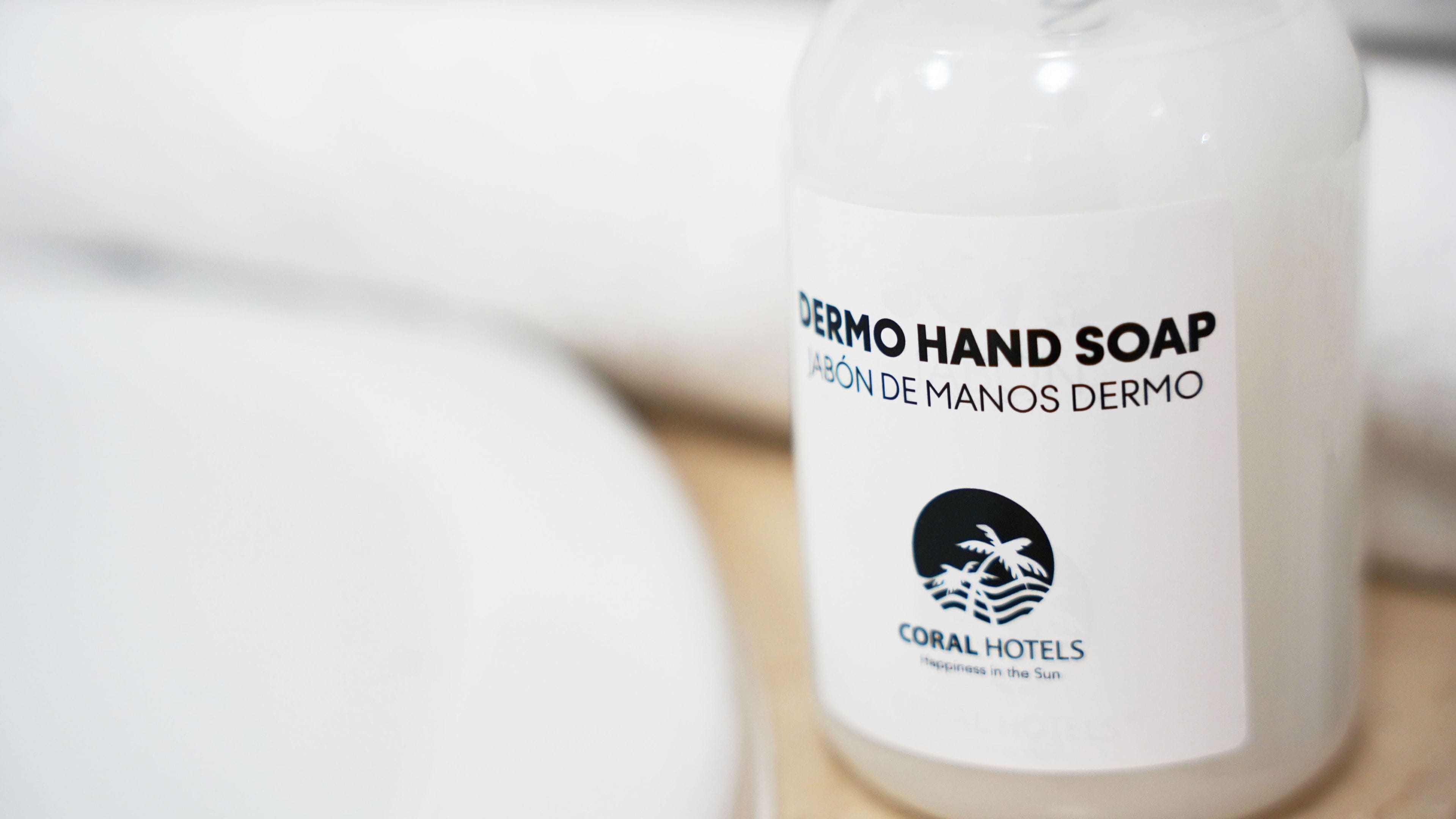 A bottle of hand soap with a label that includes 'DERMO HAND SOAP' and 'CORAL HOTELS' branding.
