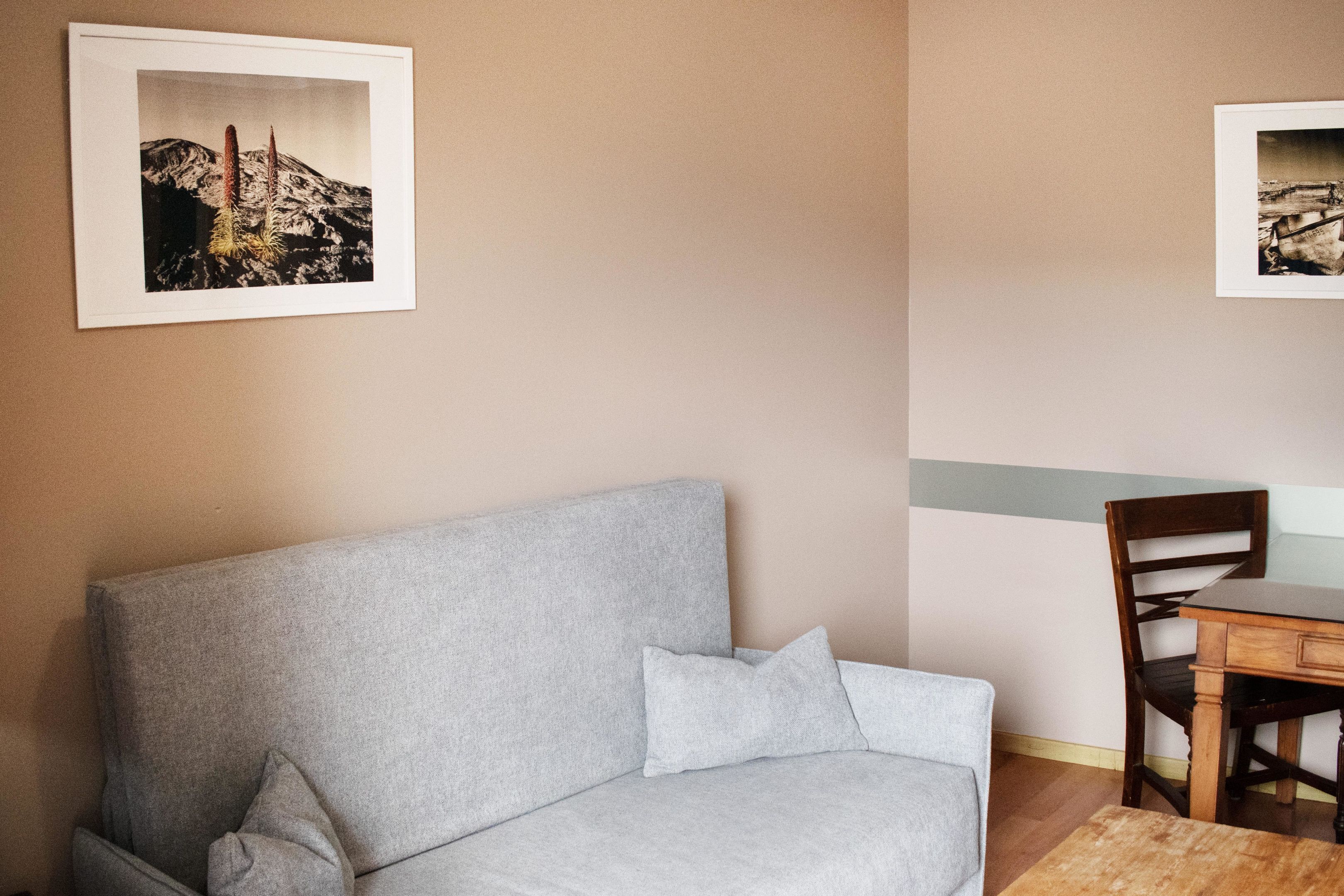 Una habitación con un sofá gris, una mesa de comedor de madera y dos cuadros en la pared.
