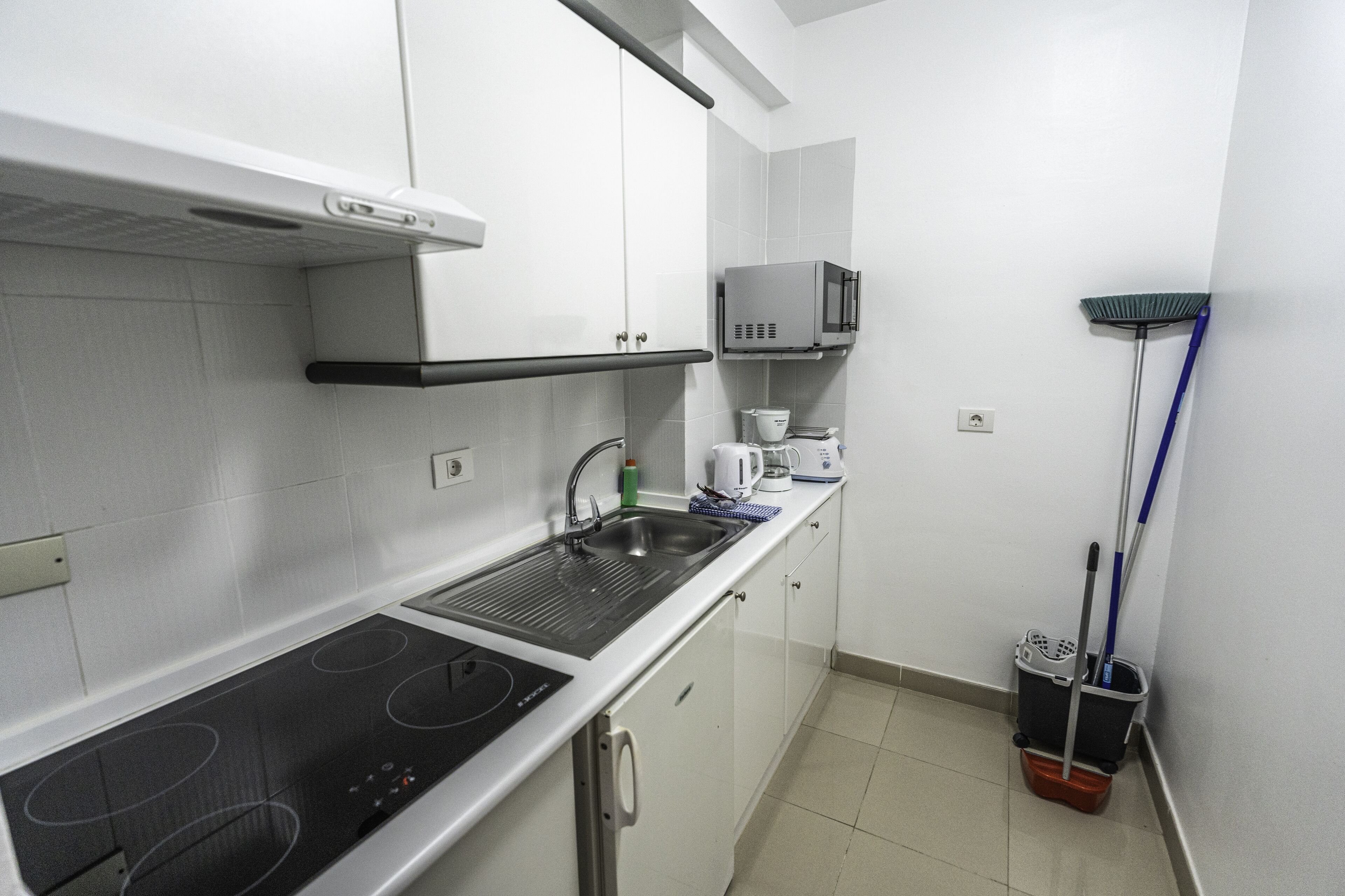 A compact kitchen with a built-in stovetop, a microwave, and a sink.