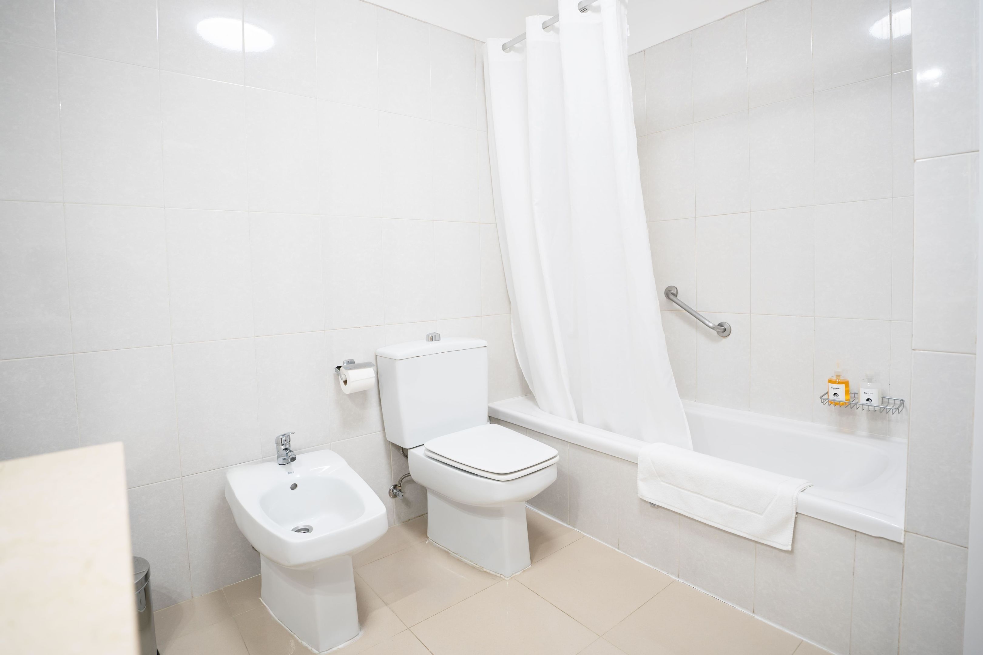 A bathroom with a toilet, bidet, and bathtub.
