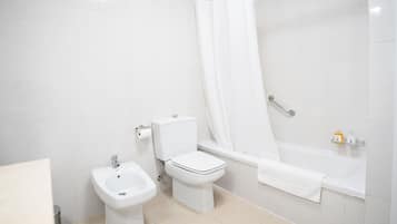 A bathroom with a toilet, bidet, and bathtub.