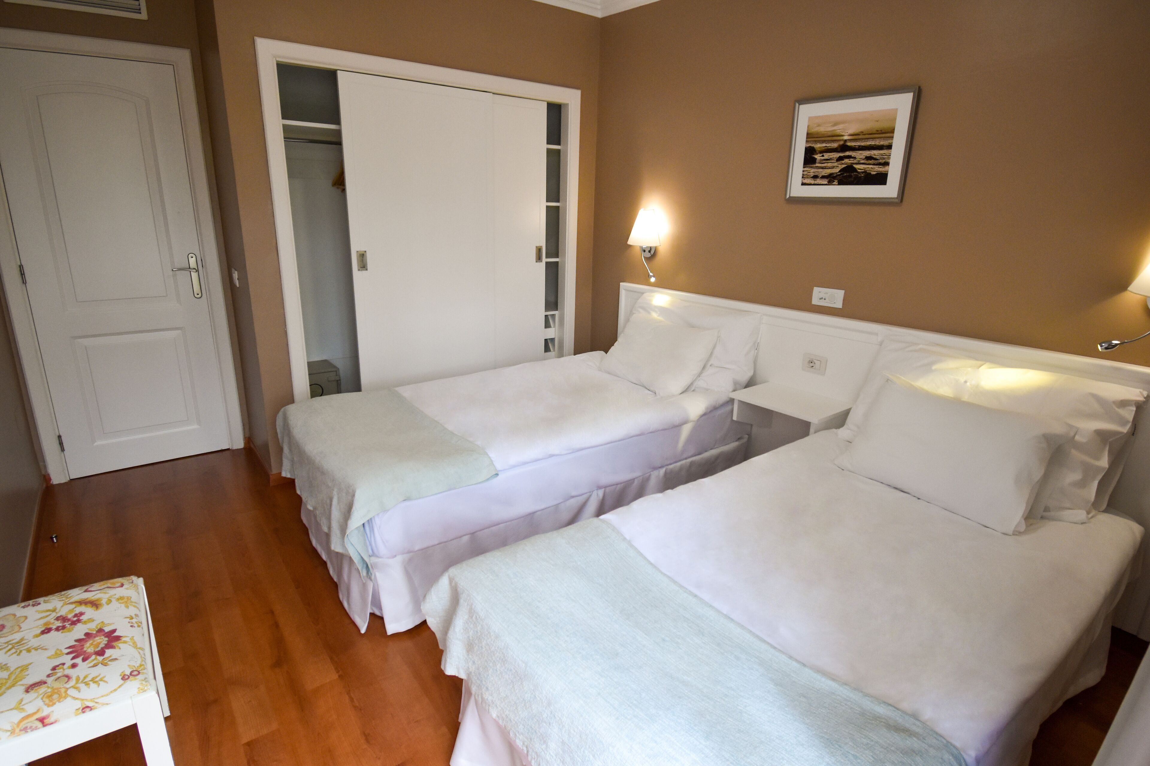 Una habitación de hotel con dos camas, un armario y una mesita de noche.