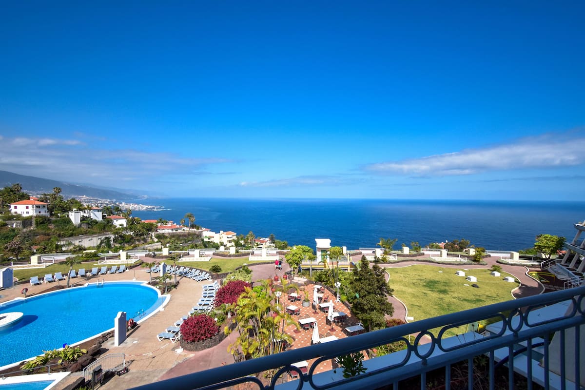 Un complexe hôtelier doté d’une piscine, de chaises longues et offrant une vue sur l’océan.