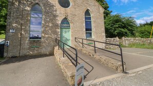 Un edificio in pietra con una porta verde, un cartello con scritto 'Bowlees' e un cartello per 'Brampton Dairy Ice Cream'.