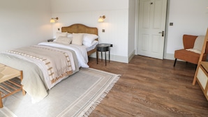 Una camera da letto con un letto di legno, un comodino, una sedia e una porta.