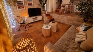 Ein modernes Wohnzimmer mit Flachbildfernseher, einer Couch, einem Couchtisch und einer Treppe, die zur Küche hinaufführt.
