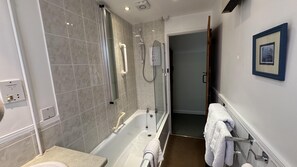 A modern bathroom with a bathtub, a shower, and a toilet. There are towels hanging on the wall and a framed picture. - Welcoming 2 Bed Charming Self Catering Cottage (Cheddar)