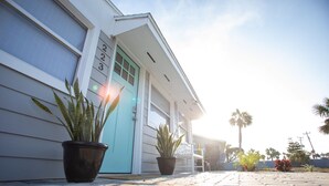 A house with a blue door, numbered 203, and two potted plants in front.