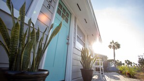 A house with a turquoise door, potted plants, and a clear sky.