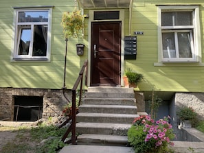 Stunning two-story house with a garden, featuring a front door with a glass panel and a small porch.