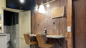 Un comedor con pared de madera, un televisor sobre una mesa y dos sillas.