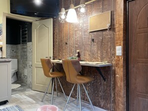 Enjoy meals at the dining table with two chairs, accompanied by a side table and a flat-screen TV.