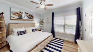 A bedroom with a large bed, a ceiling fan, a window with blinds, a bookshelf, and a painting on the wall. - Gorgeous 3BR Condo in FOLEY near OWA/THE BEACH!! (Foley)