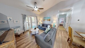 A spacious living room with a grey sofa, a coffee table, and a ceiling fan. - Gorgeous 3BR Condo in FOLEY near OWA/THE BEACH!! (Foley)
