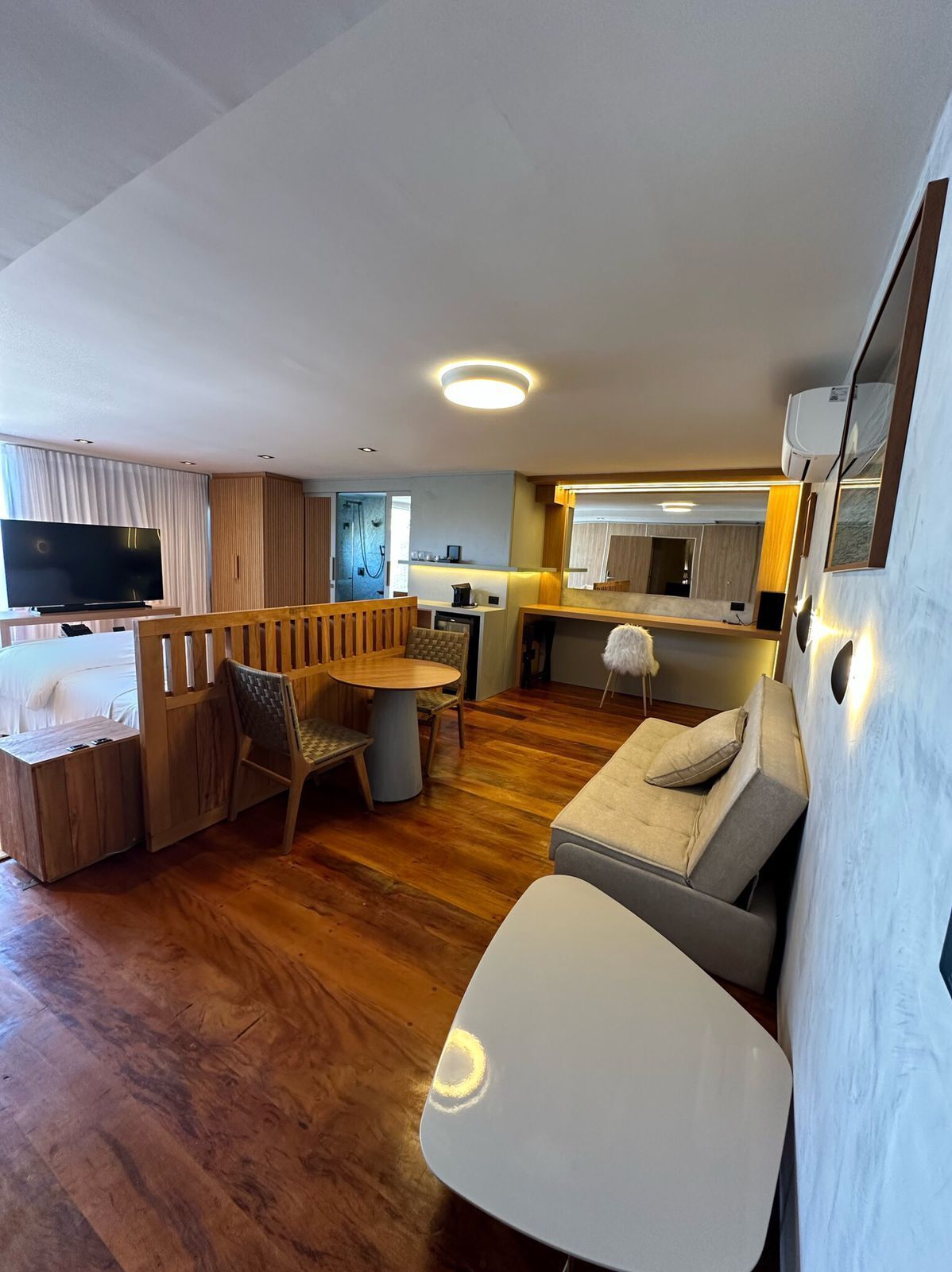 Een ruimtelijk ingerichte leefruimte met kitchenette, eethoek en zithoek met een bank en een klein tafeltje.